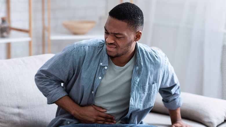 A man holding his stomach and looking distressed