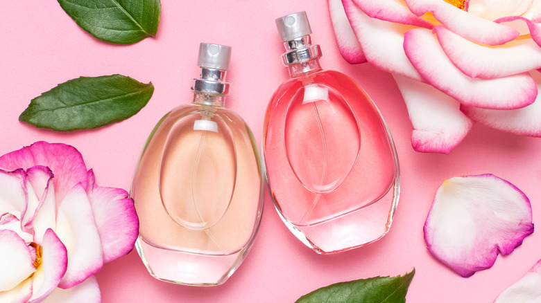 Two perfume bottles on floral pink background