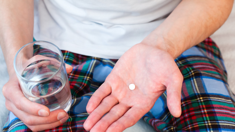 Close up of man holding water and pill