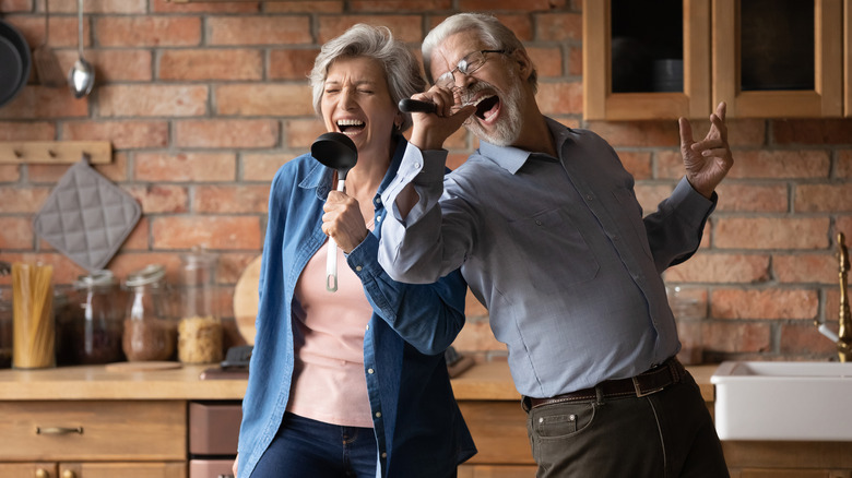 happy elderly couple singing with utensils