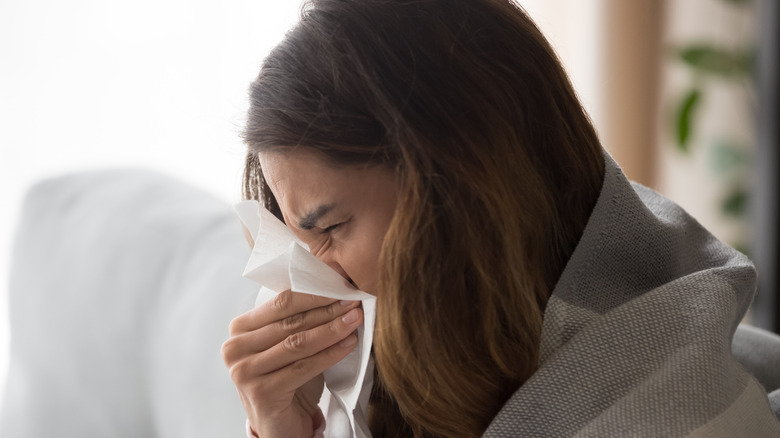 Sick woman blowing nose