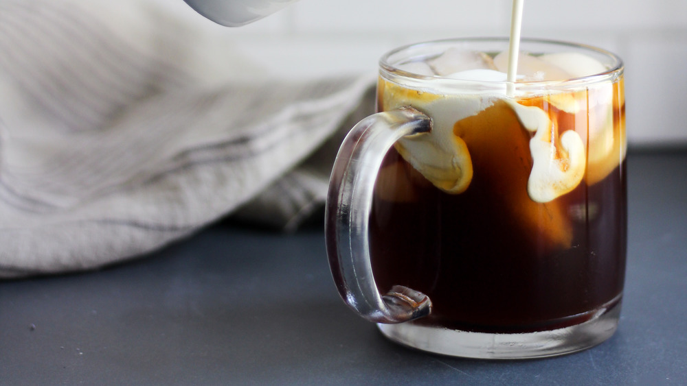 iced coffee being topped with thick white creamer 