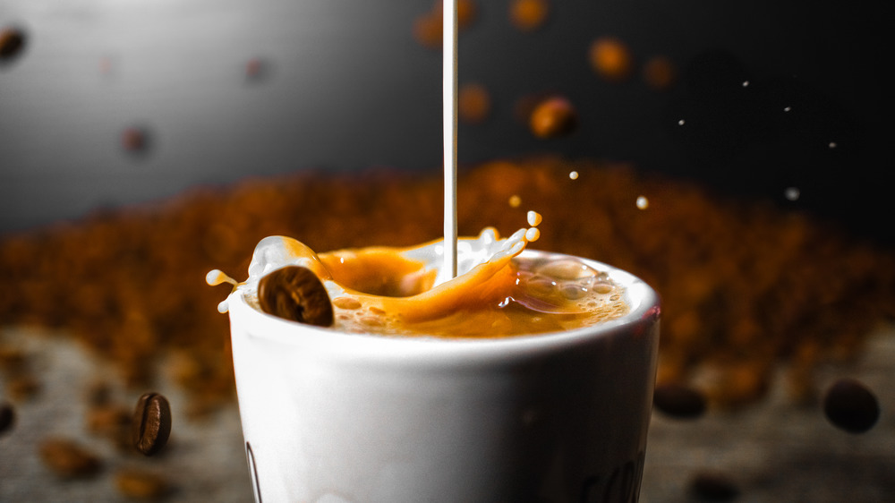 creamer falling into a white mug of coffee 