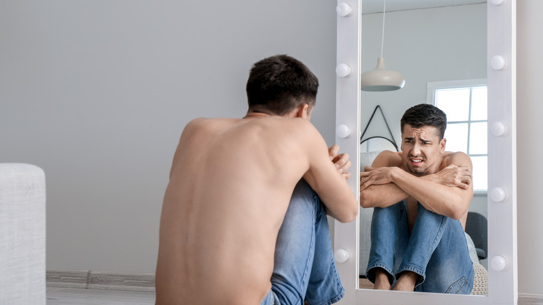 Man with eating disorder looks in mirror