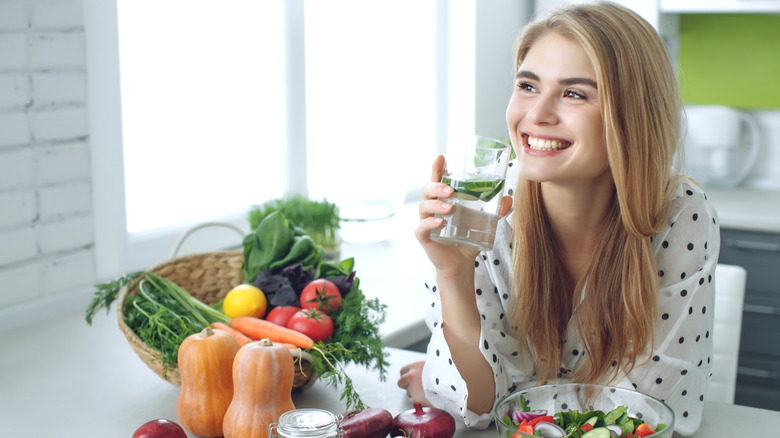 Smiling woman in kitchen holding glass of water