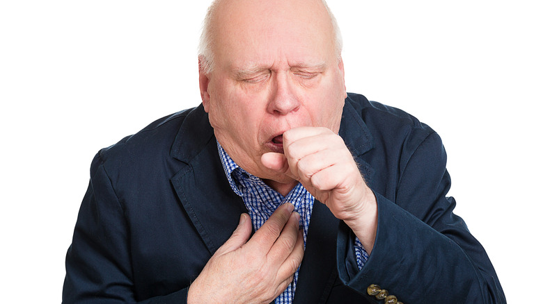 man coughing and holding chest