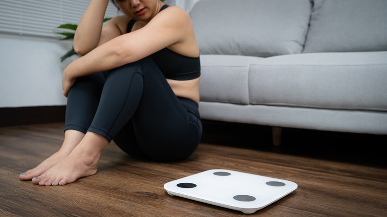 Woman sitting next to scale