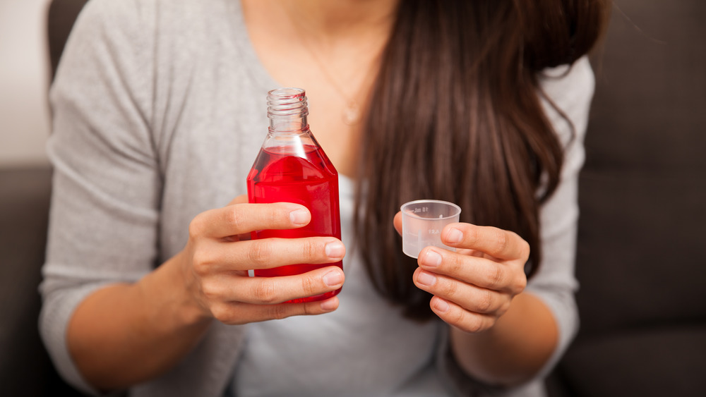 woman holding bottle of cough syrup