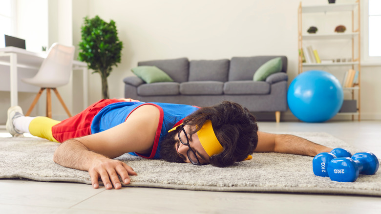 A man laying on the floor surrounded by exercise equipment