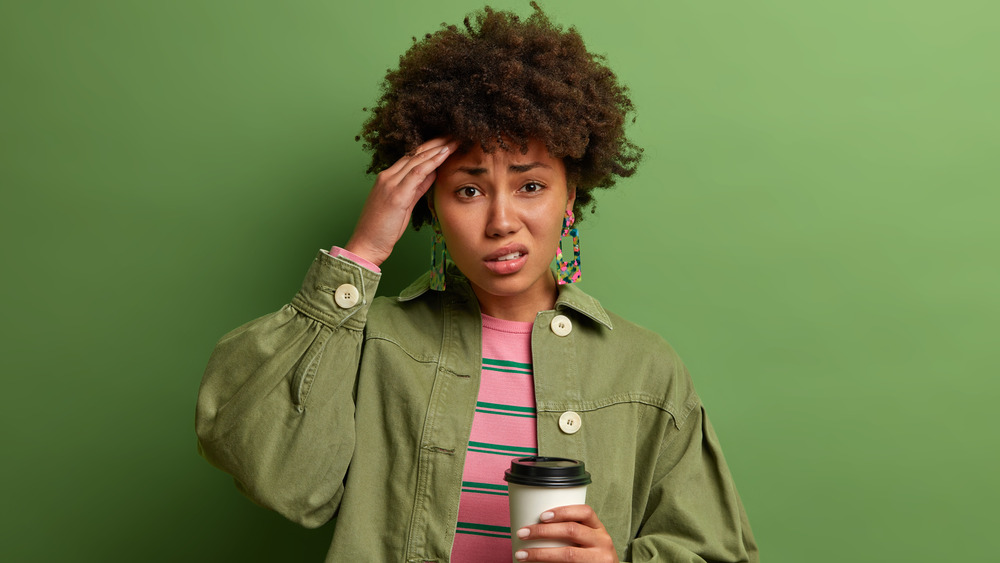 Woman with headache holding coffee