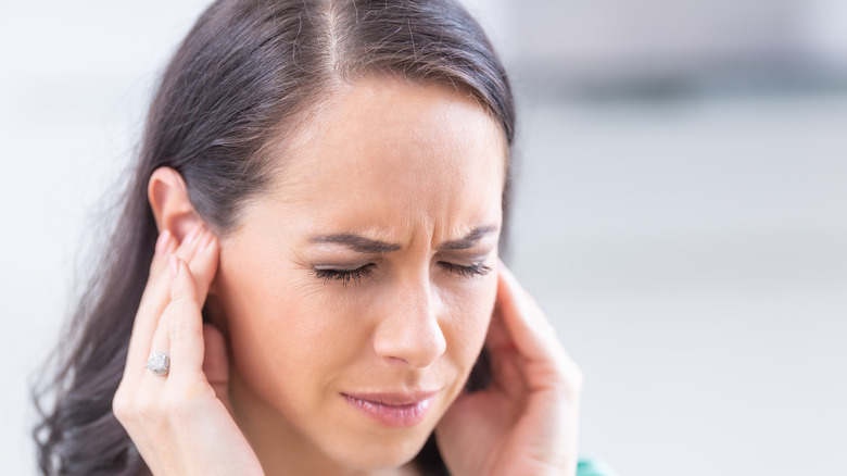 woman pressing hands against her ears