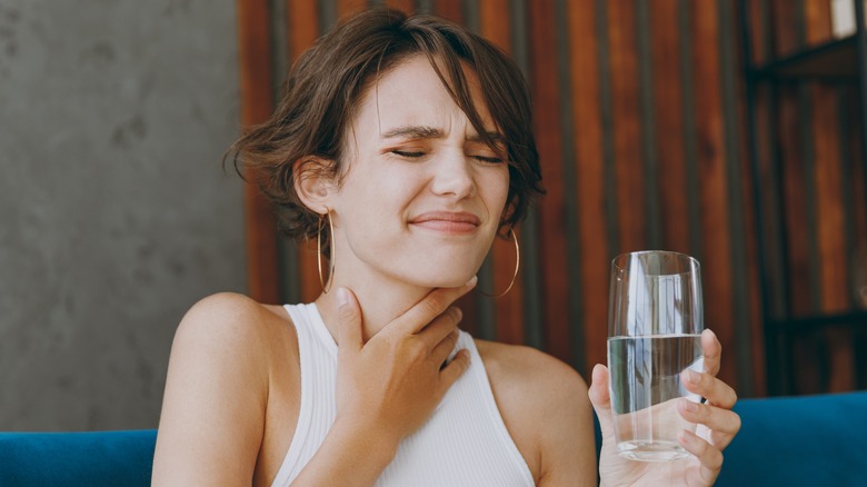Woman with sore throat holding water