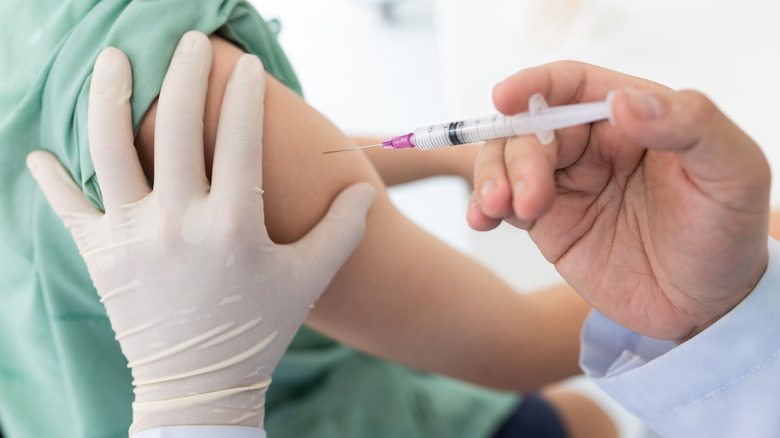 medical personal administering a vaccine in the upper arm of a female 