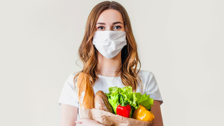 Woman holding groceries and wearing a mask