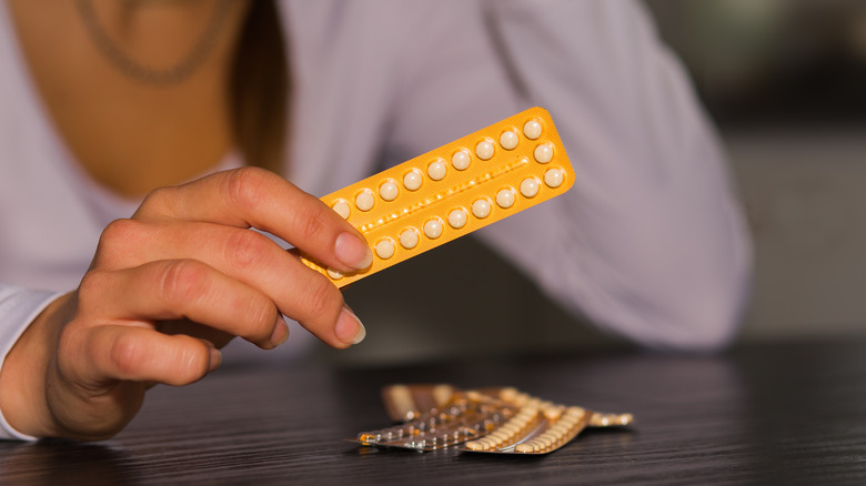 A woman holding a pack of contraceptive pills