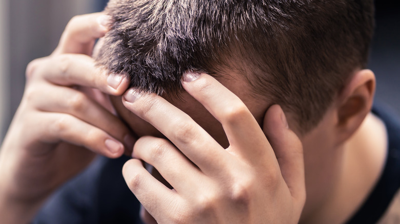 Man with anxiety sits with his head in his hands
