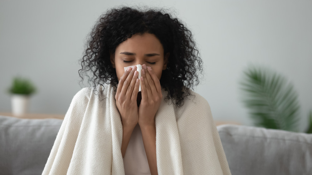 woman with blanket blowing nose