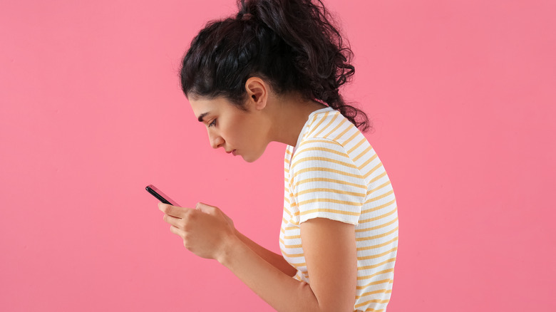 woman using phone with bad posture