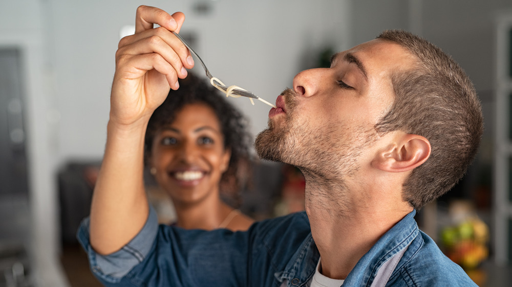 young man tasting a forkful of spaghetti 