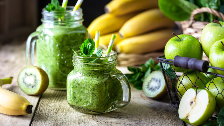 Green smoothies and fresh fruits on a table