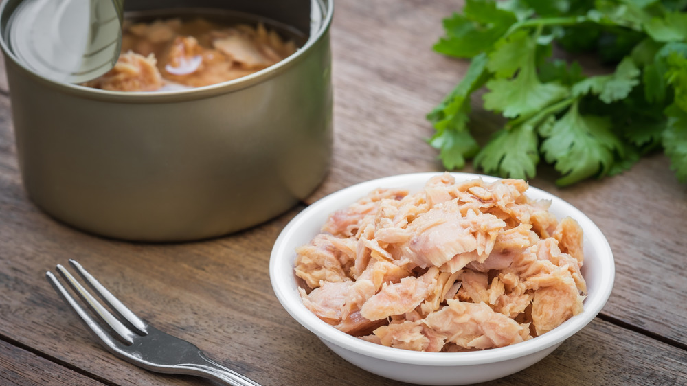 An open can of tuna next to tuna in a bowl