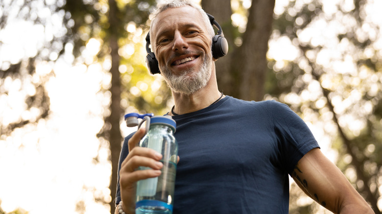 Shirtless man drinking bottled beverage