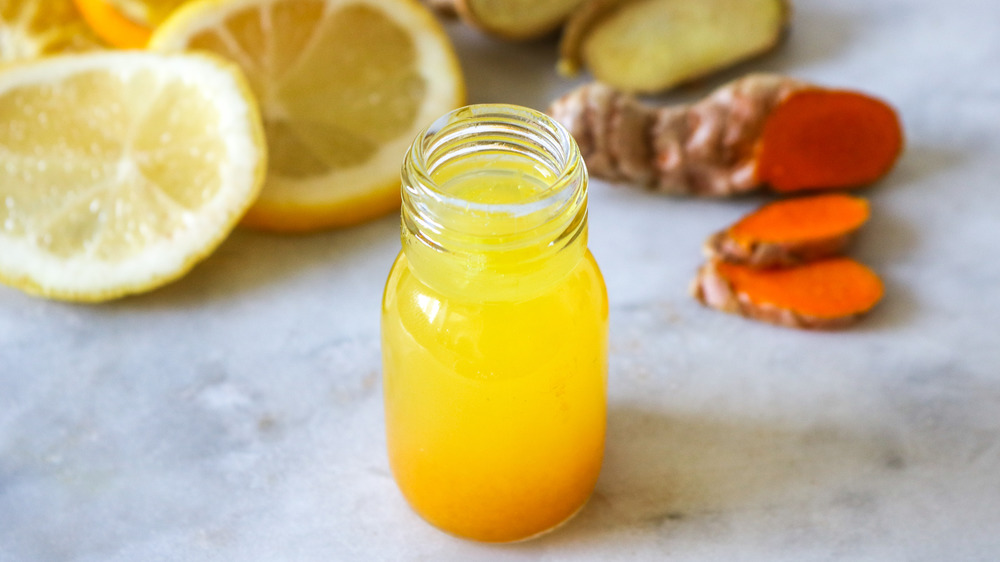 Ginger shot surrounded by fruits 