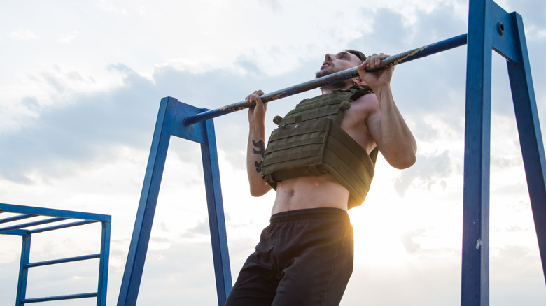 man doing pull ups with a weighted vest 