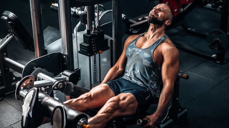muscular man doing leg extensions at the gym