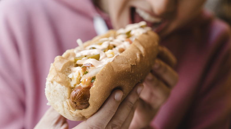 A woman biting into a hot dog on a bun