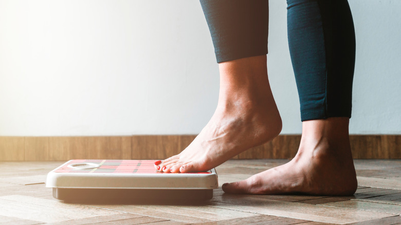 person stepping on weighing scales