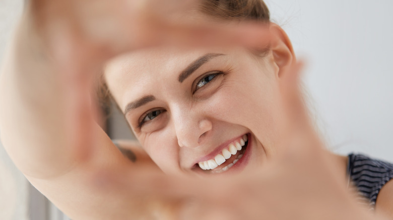 Smiling woman looking through her hands