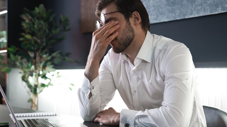 man rubbing eyes due to stress