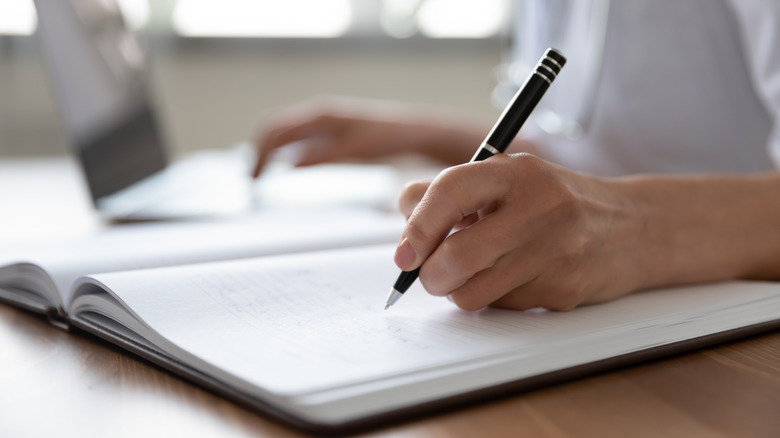 close up of a woman's hand writing in a journal 