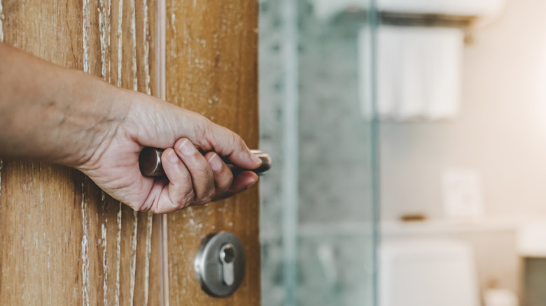 person opening door to toilet