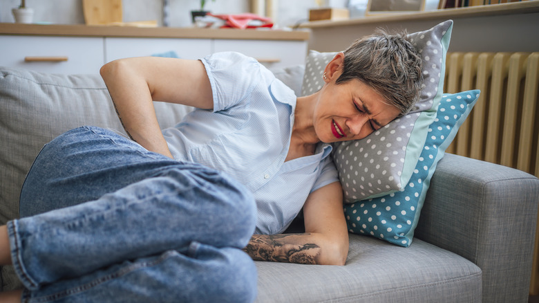 woman lying on her sofa with constipation pain