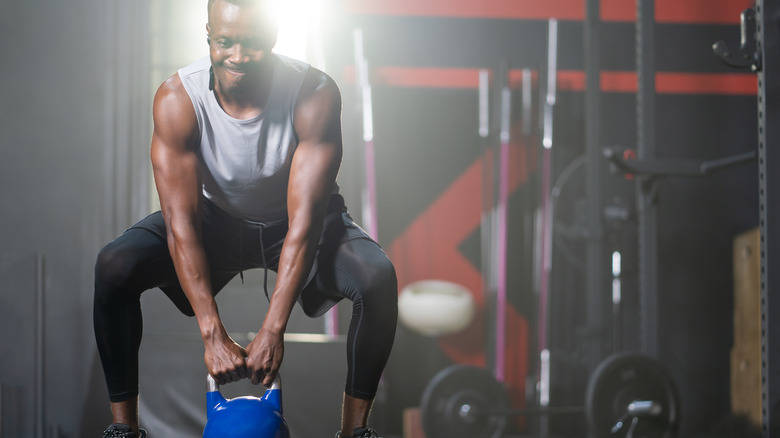 A man holding a kettlebell's handle as the weight rests on the floor