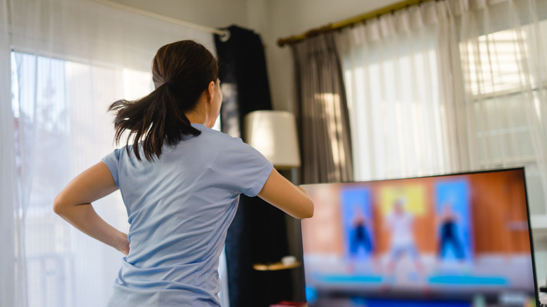 A woman exercising in front of her tv with a fitness program on
