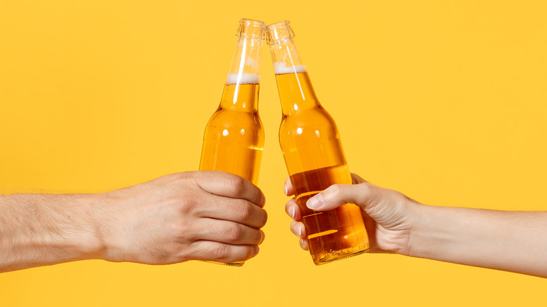 man and woman's hands, clinking beer bottles
