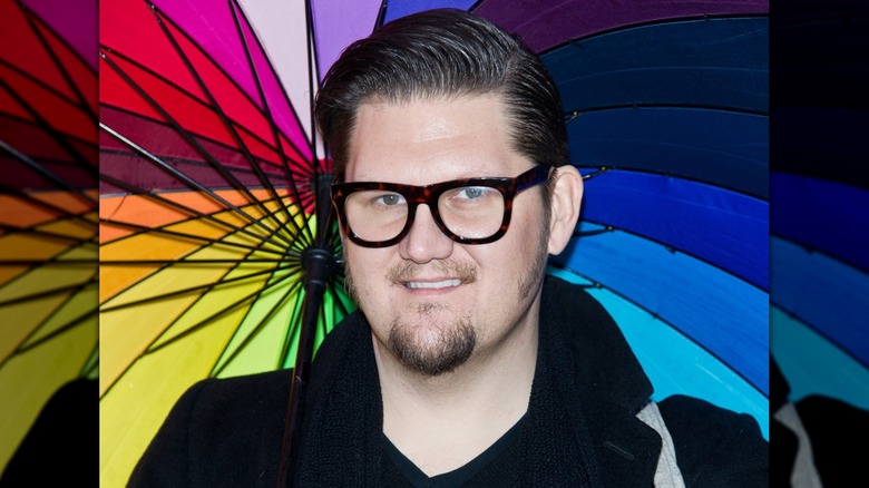 Jay McCarroll smiling while holding a rainbow umbrella