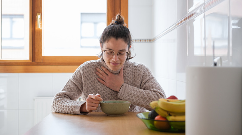 Woman with sore throat eating soup