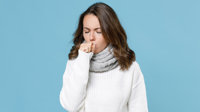 a woman coughing into her hand 