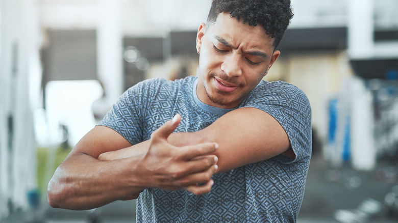 man touching and looking at elbow