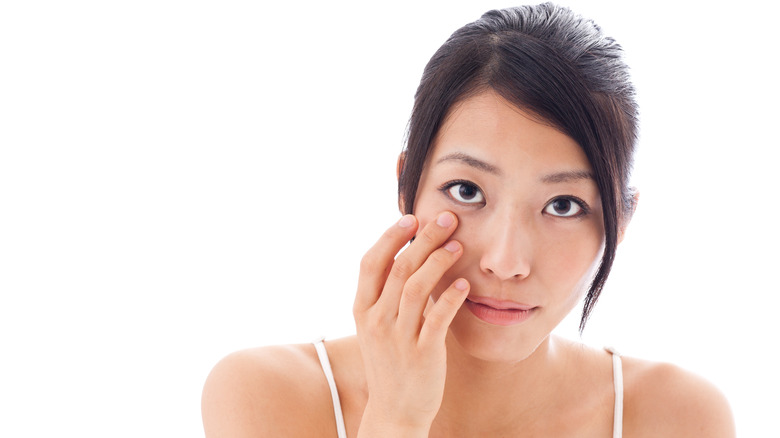 Woman examines her eye for signs of broken blood vessels