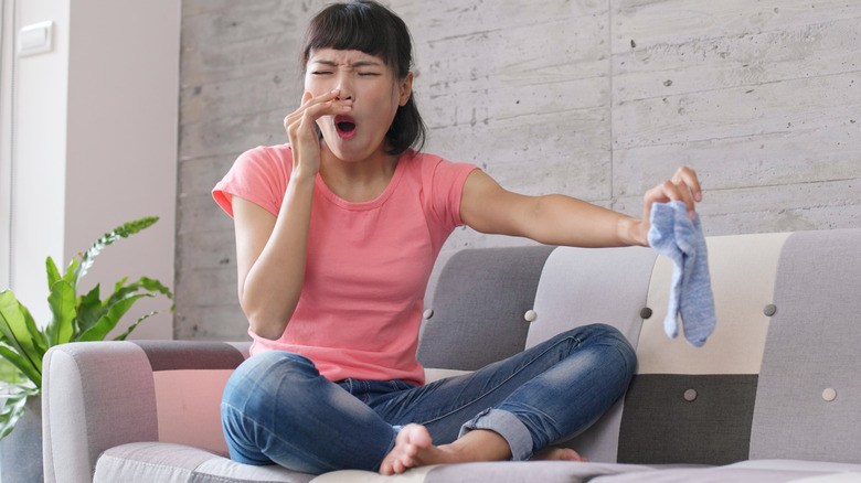 woman holding socks over smelly feet