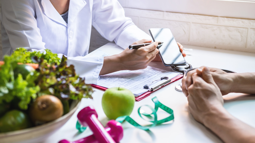 Dietitian offering consultation to patient with fruits on table