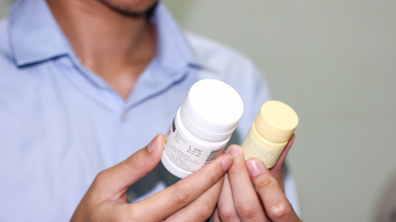 Man comparing two different pill bottles 