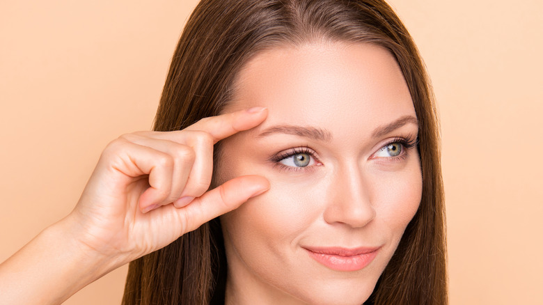woman smirking and touching side of her face
