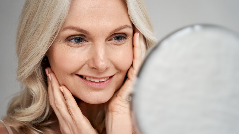 older woman looking in mirror smiling