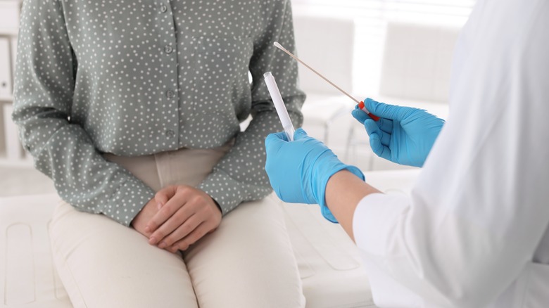 woman in clinic holding private area